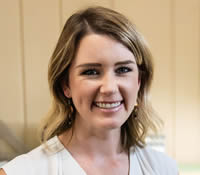 a woman in a white top smiling at the camera