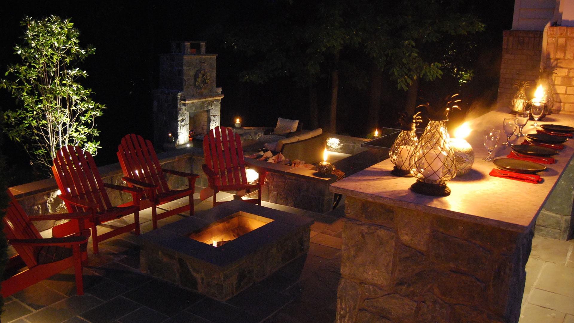 a fire pit surrounded by red chairs and lit candles