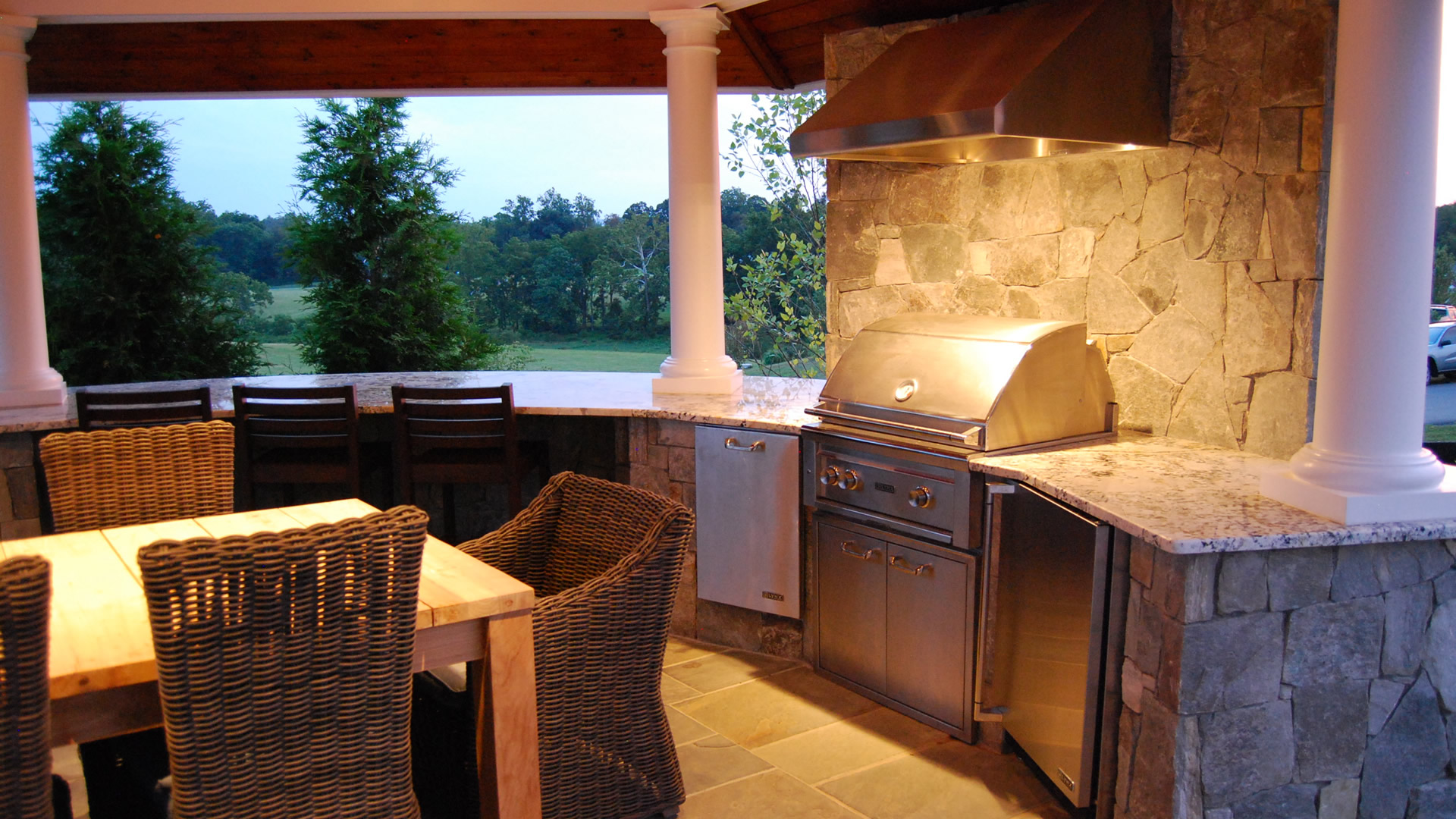 an outdoor kitchen with a grill and dining table