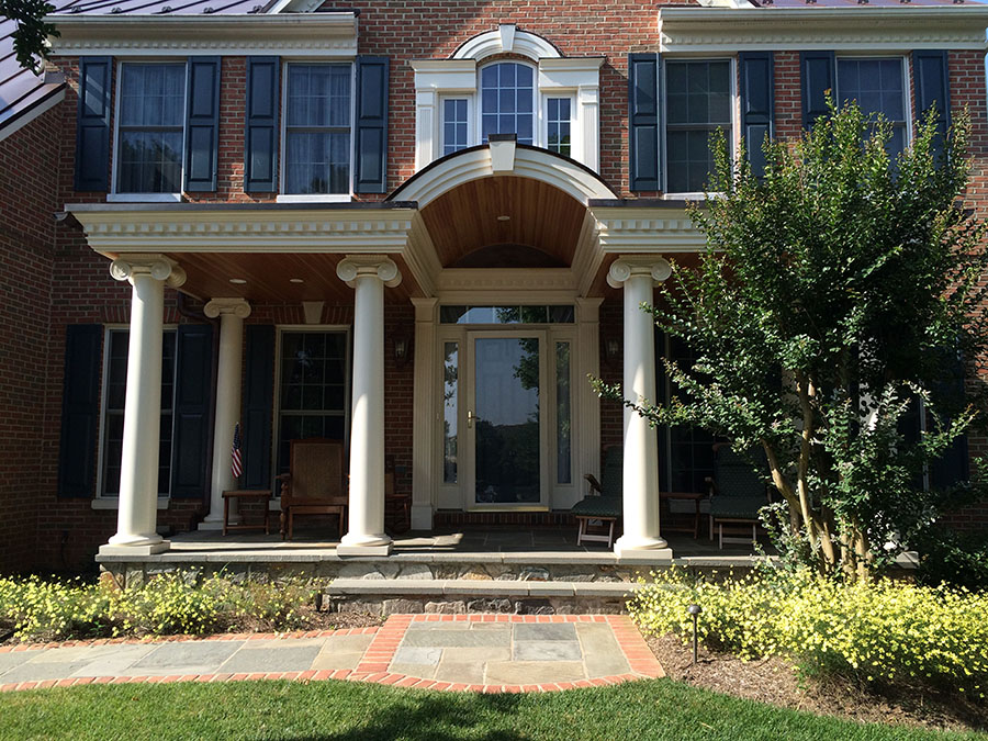 A combination front walkway with stone tiles bordered by brick on the outside