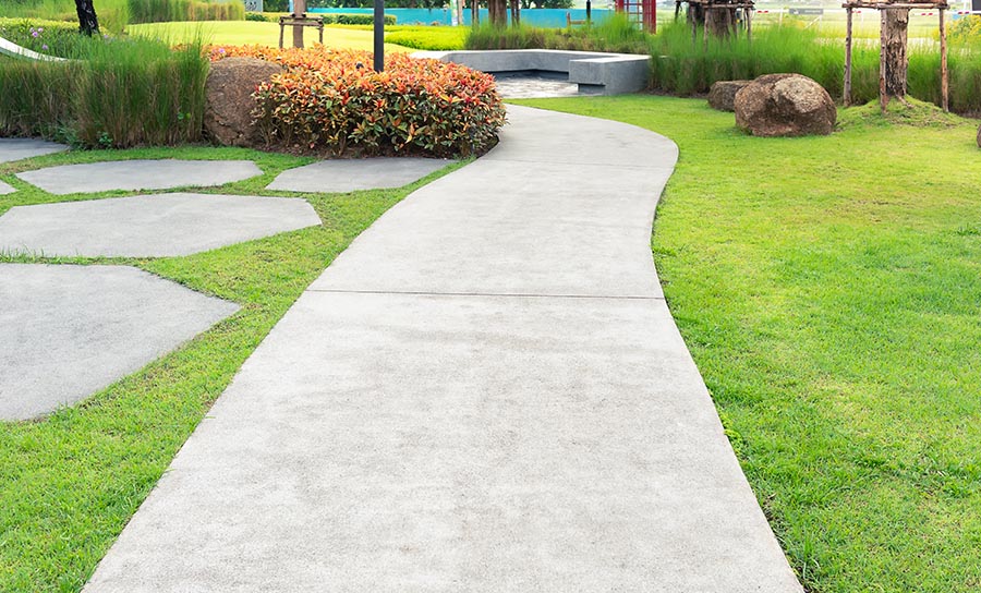 A concrete pathway snaking vertically through an elaborate lawn and garden