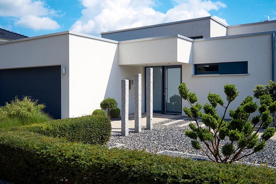 A white house with a gravel walkway leading to the front door with stepping stones between the gravel stones