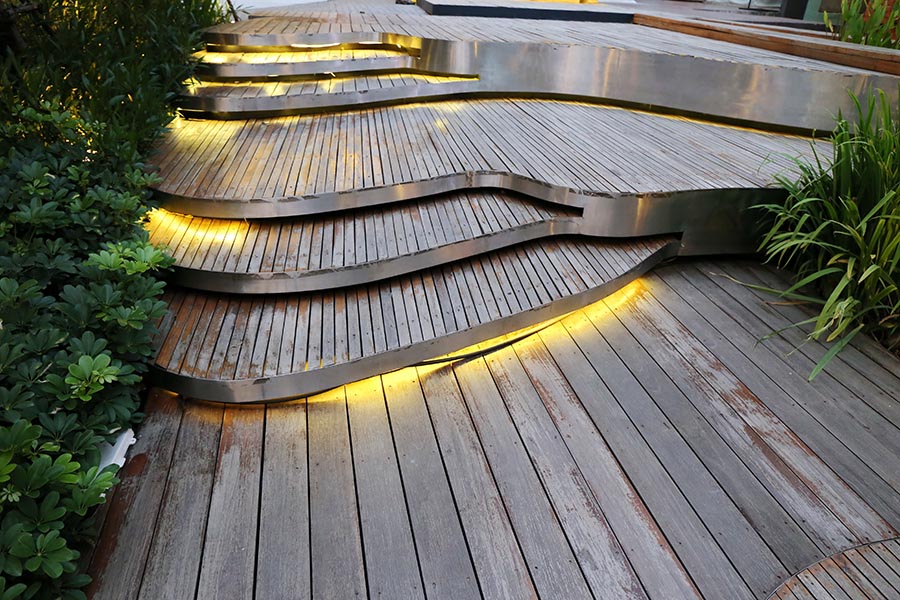 A series of wood plank steps in front of a house with lowlights marking the steps