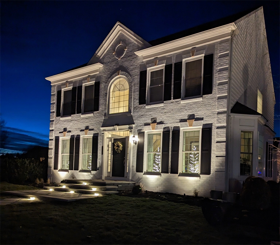 A white house at night being lit up by outdoor lighting from Outdoor Spaces