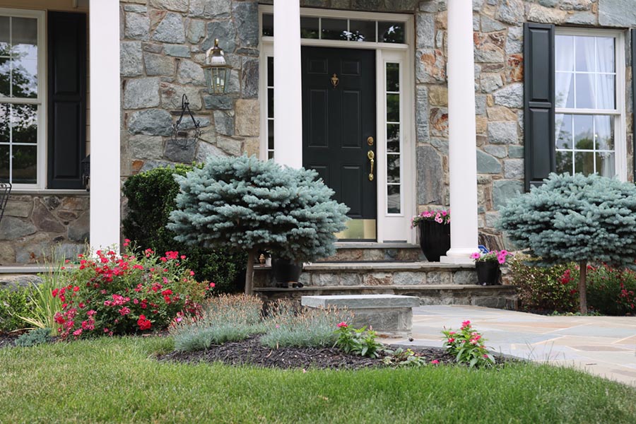 A stone front porch of a home with white greek columns