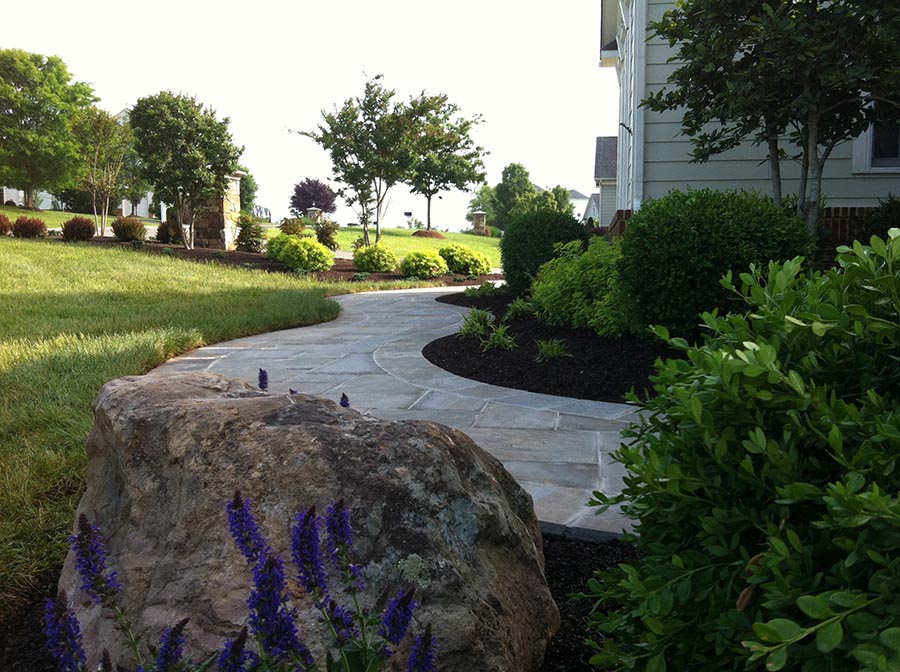 A winding stone pathway with a big rock in the foreground