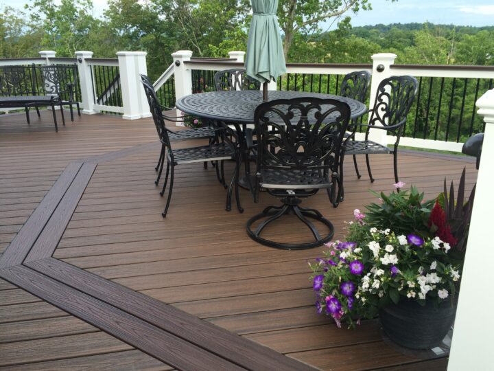 A composite wood deck with a black metal table and four chairs surrounding it 