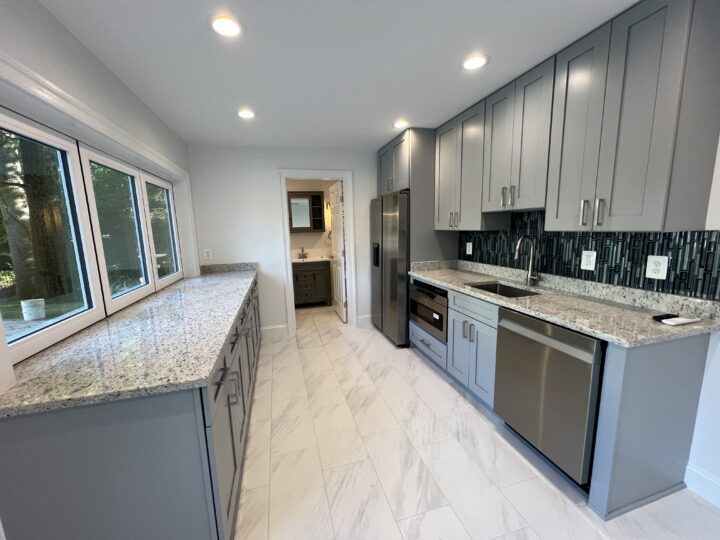 A kitchen inside of a pool house, with marble-top counters on each side of the room.