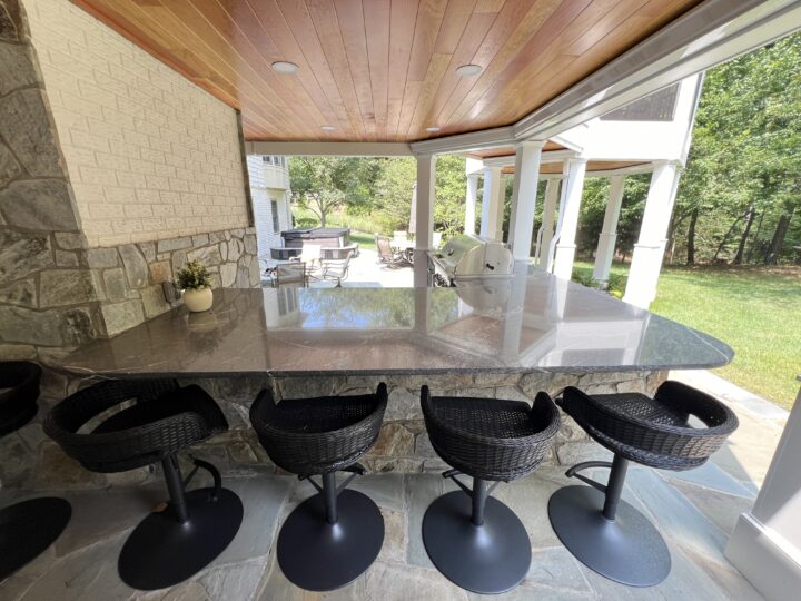 A flat marble countertop outside with tall bar chairs lined up against it