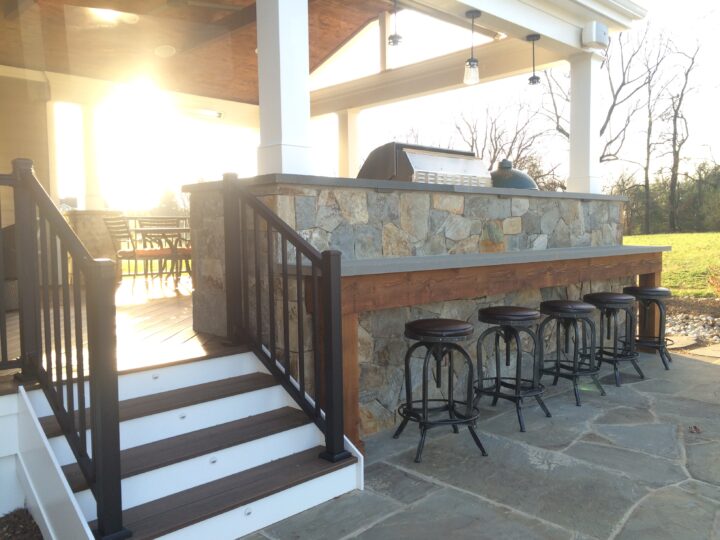 A staircase leads up to a porch with a grill up against the edge.