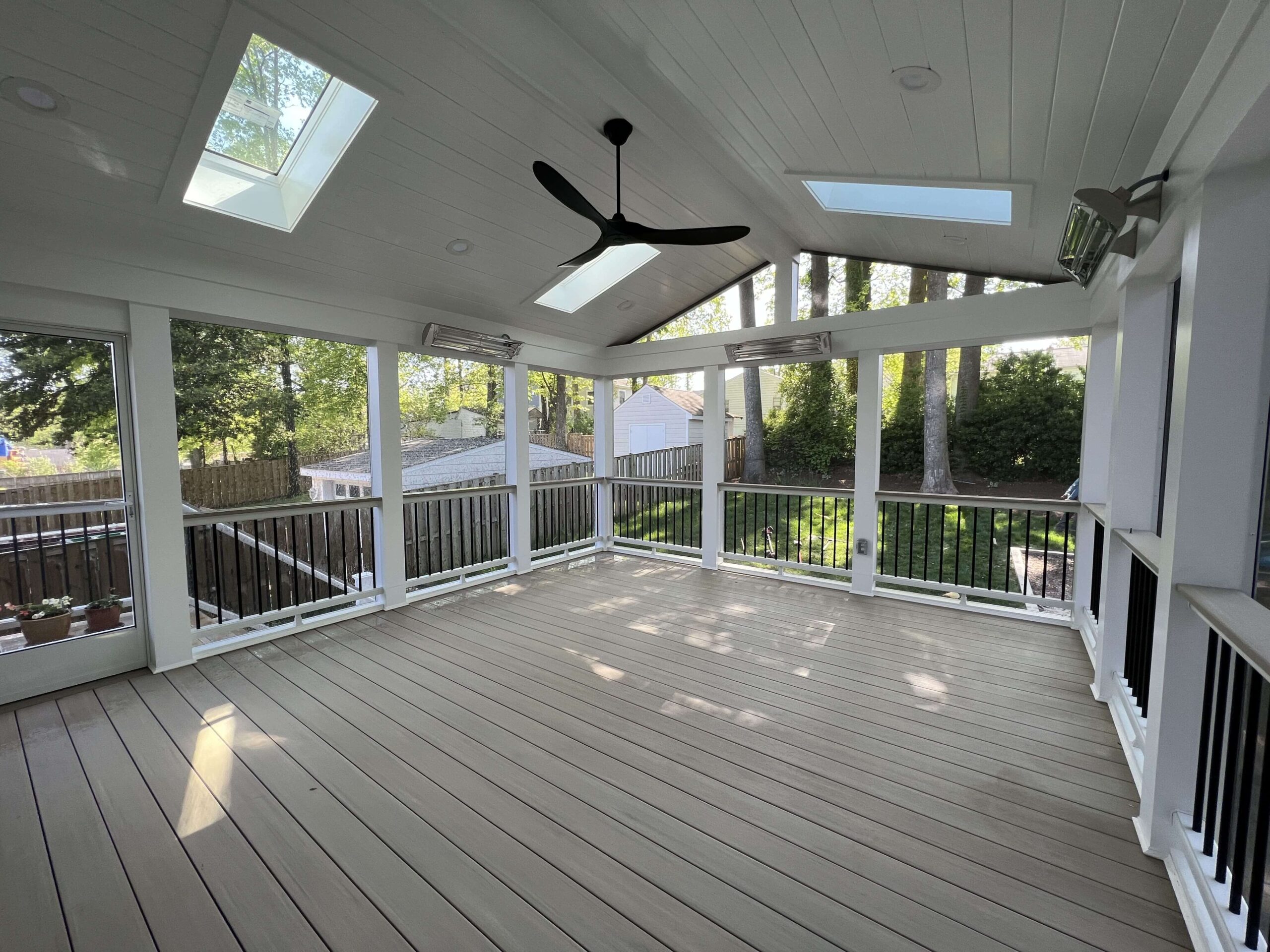 A screened-in porch with white walls and a ceiling fan.