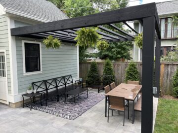 A modern black pergola with dual seating zones.