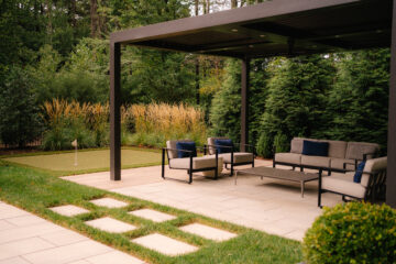 A louvered aluminum pergola with lounge seating and a putting green.