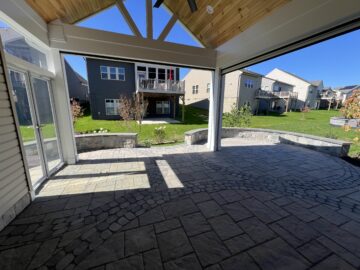 A vaulted ceiling porch with a stone patio and garden views.