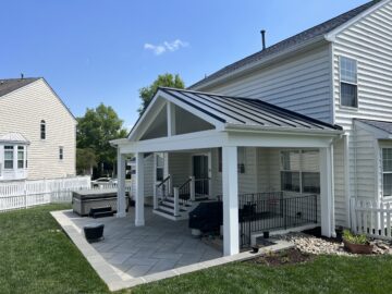 A covered porch with standing seam roof and an open patio.