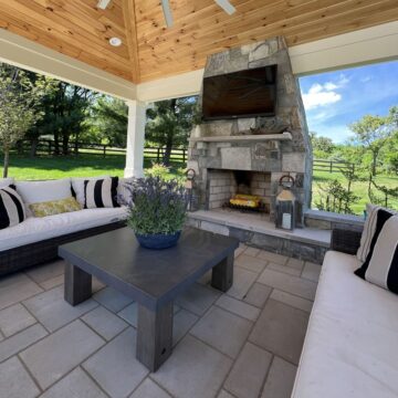 An outdoor fireplace with stone-veneer masonry fireplace and a wrap-around hearth.