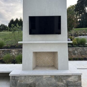 A tall masonry fireplace with stucco and a marble mantel.