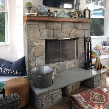 An outdoor fireplace with a wood-burning insert with built-in wood storage.