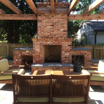 An outdoor fireplace made of brick with extended seat walls.