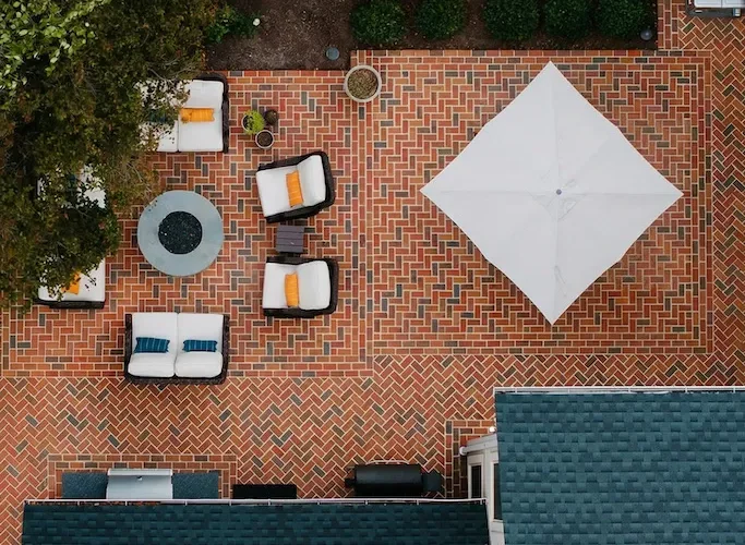A brick patio with a fire pit and umbrella
