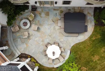 Organic stone patio with a covered hot tub, a fire pit, and dining area.